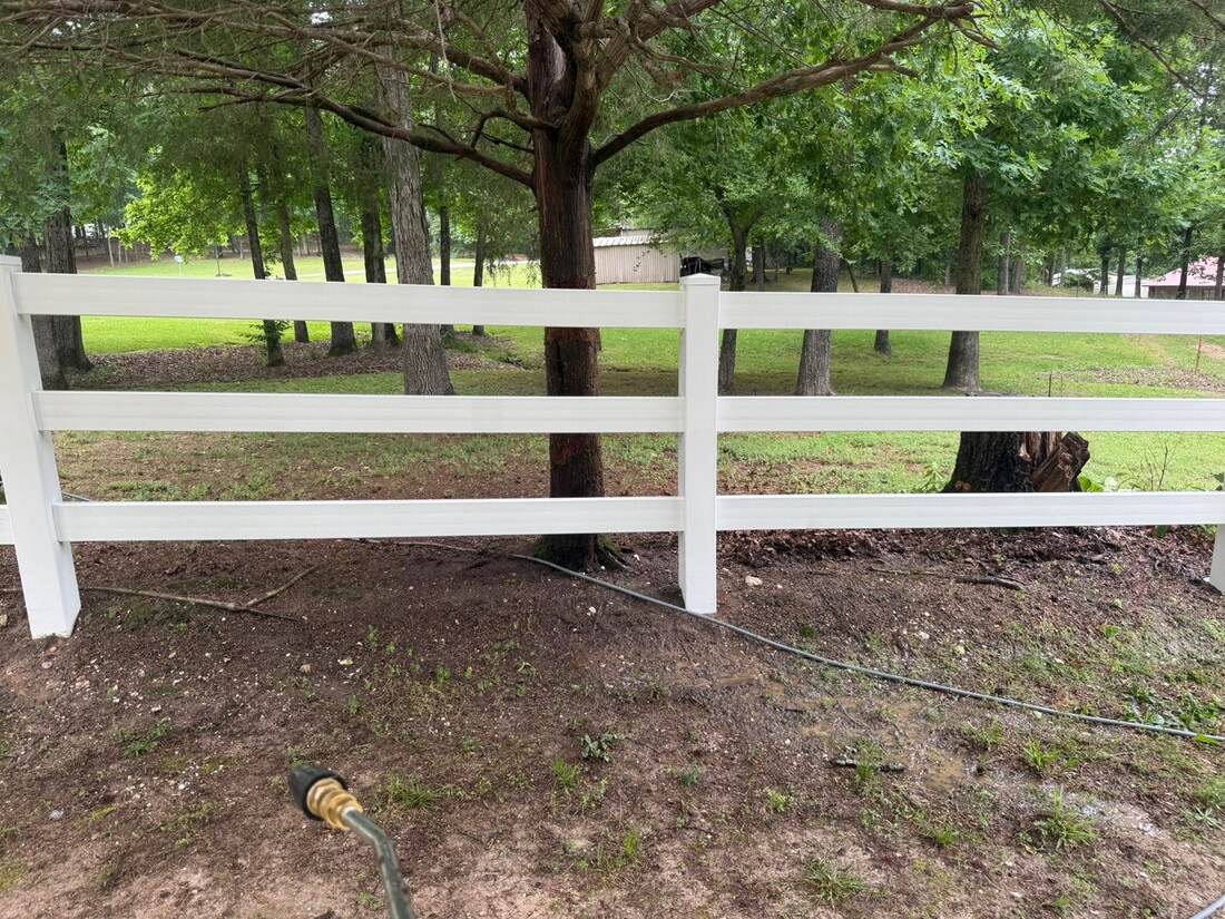 Bright white rail fence after cleaning, pressure washer wand in view